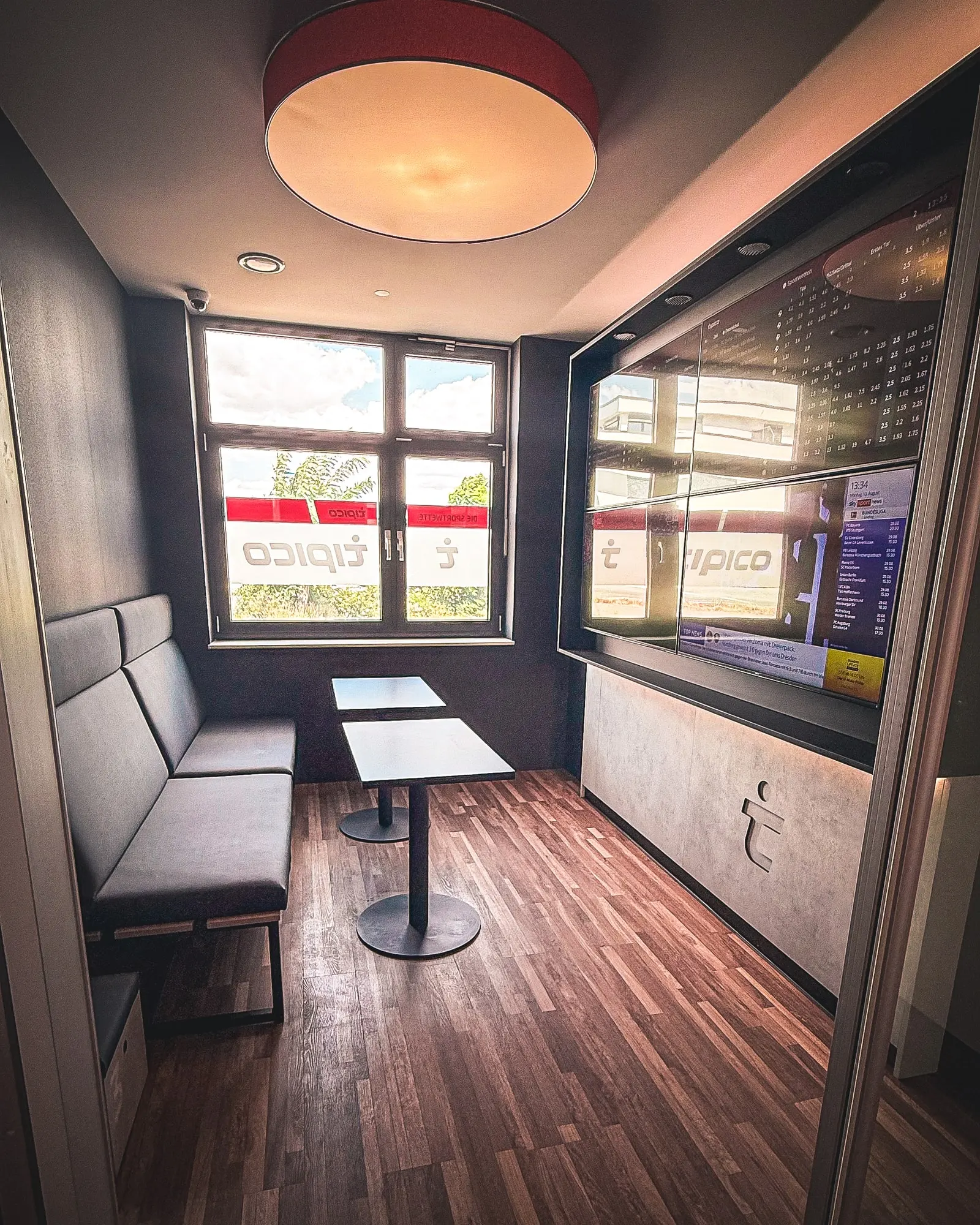 Private Room im Tipico Grünstadt: separater Raum mit Sitzbank, zwei Tischen und eigener Bildschirmwand